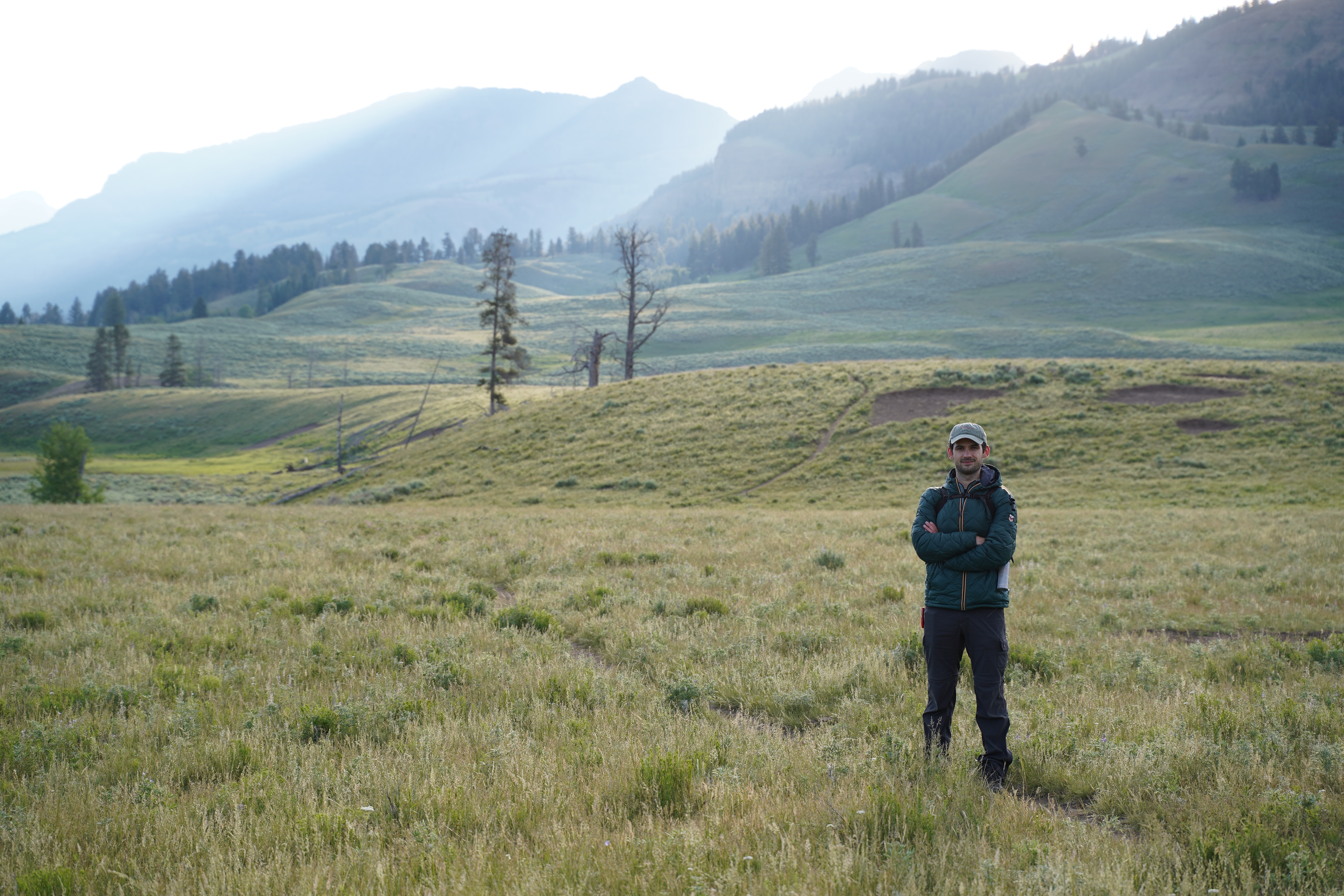 Ethan in a wide grass valley with mountains behind him.